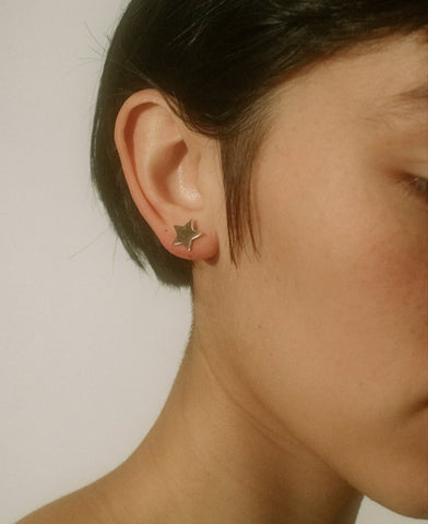 Close-up of a person wearing a star-shaped earring against a plain background
